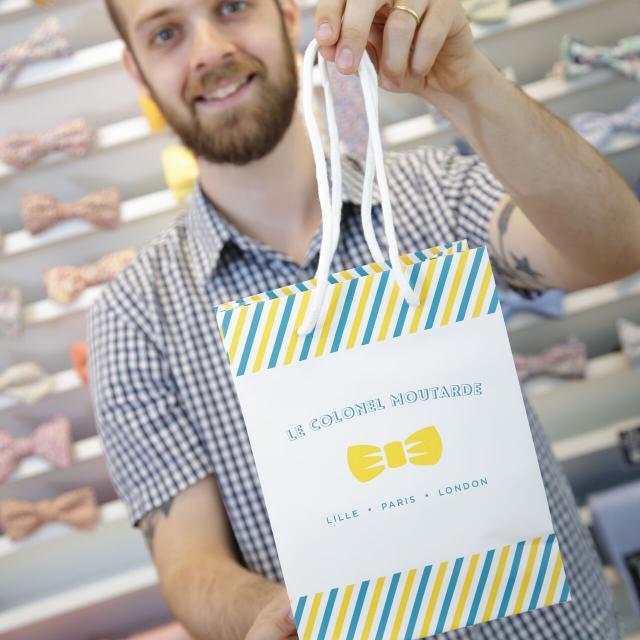 Detailaufnahme Mann reicht Einkaufstüte mit Logo 